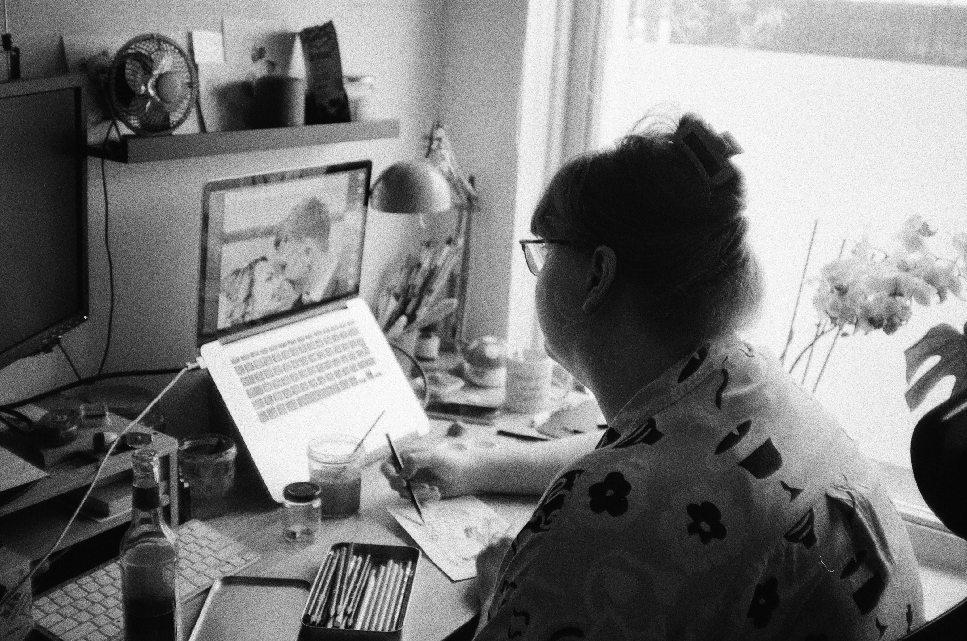 Zwart-wit foto van Debora die achter de computer aan het illustreren is